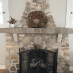 Stone fireplace with a decorative wreath and modern accents in the living room of Rosslyn Retreat