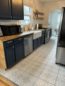 Modern kitchen with navy cabinets, butcher block countertops, a farmhouse sink, and stainless steel appliances at Rosslyn Retreat.