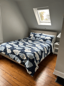 Upstairs bedroom with a queen-sized bed, skylight, and natural wood floors at Rosslyn Retreat.