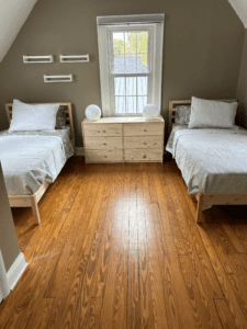 Upstairs bedroom with two twin beds, a dresser, and natural wood floors at Rosslyn Retreat.